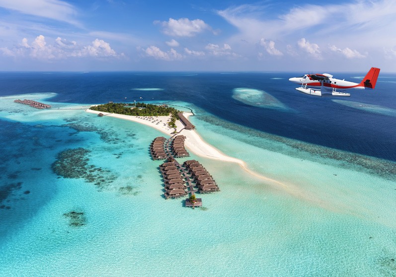 sea plane and over water bungalows against the blue waters of the Maldives